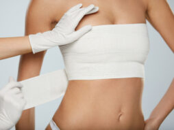 doctor wrapping woman's chest after breast augmentation surgery