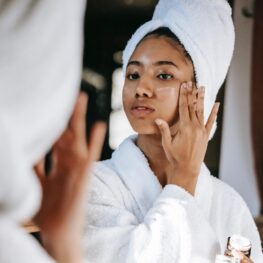 woman wearing a robe applying skin cream